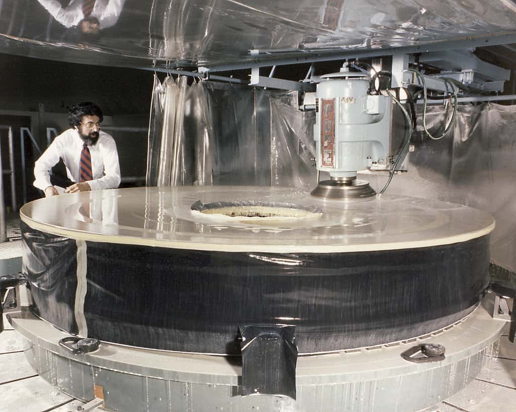 Sur cette image, le miroir principal du télescope spatial Hubble dans l’usine de fabrication d’optiques Perkin-Helmer Coroporation. Plus d’une décennie avant que son minuscule — mais non moins important — défaut ne soit découvert. © Nasa