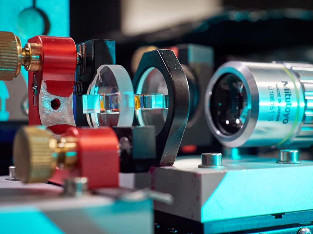 Le microrésonateur optique utilisé dans leur expérience par les chercheurs de l’université de Bonn (Allemagne). En jaune, on devine le colorant qui refroidit les photons. Et à droite, un microscope pour observer la lumière émise. © Gregor Hübl, Université de Bonn