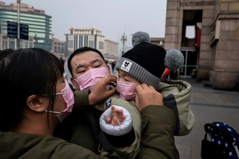 Devant la gare de Pékin, une famille revêt des masques de protection. © Nicolas Asfouri, AFP 