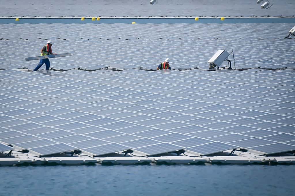 Des techniciens travaillent sur les panneaux photovoltaïques de la centrale flottante O'Megal, le 30 juillet 2019 à Piolenc, dans le Vaucluse. © Gérard Julien, AFP