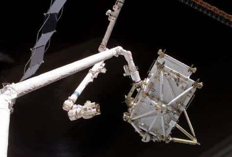 Transfert de la portion de poutre P5 depuis la soute de Discovery et l'ISS. L'élément passe ainsi du bras robotisé Canadarm de la navette à son homologue Canadarm 2 de l'ISS, une véritable poignée de mains en orbite ! Crédit NASA.