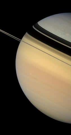 Ombres tournantes. Les scientifiques étudiant Saturne n'ont pas encore précisément déterminé la cause de la différence de couleur du nord au sud. Les survols par les sondes de la Nasa des années '80 montraient un disque planétaire plus uniforme, alors que Saturne se trouvait plus près de l'équinoxe. Ils spéculent qu'il s'agit d'un effet saisonnier. Position de Cassini : 0,5° d'inclinaison nord par rapport au plan des anneaux. Couleurs naturelles (filtres rouge, vert et bleu). Date : 4 février 2007. Distance : 1,2 million de km.