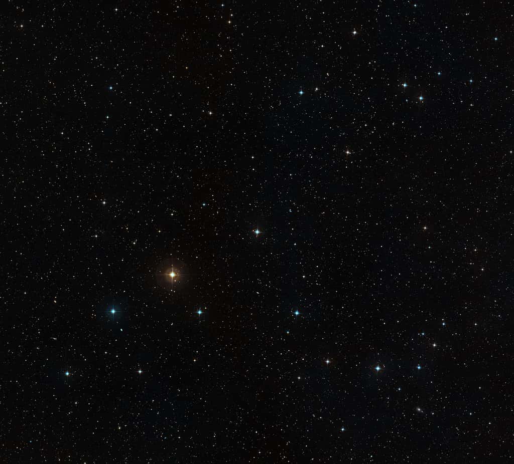 Cette image à grand champ montre le ciel autour de l'étoile HD 10180, qui apparaît comme une étoile assez brillante juste au-dessous du centre. L'image a été créée à partir de photographies prises avec des filtres rouge et bleu. Les halos colorés autour des étoiles sont des artefacts dus au procédé photographique. Crédit : ESO, <em>Digitized Sky Survey 2</em>/Davide De Martin.