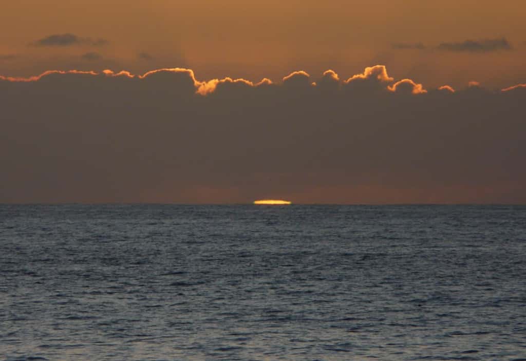 Le Soleil plonge dans la mer. Avant sa disparition complète la diffraction commence à faire virer au vert la bordure du disque la plus proche de l'horizon. Crédit J-B Feldmann 