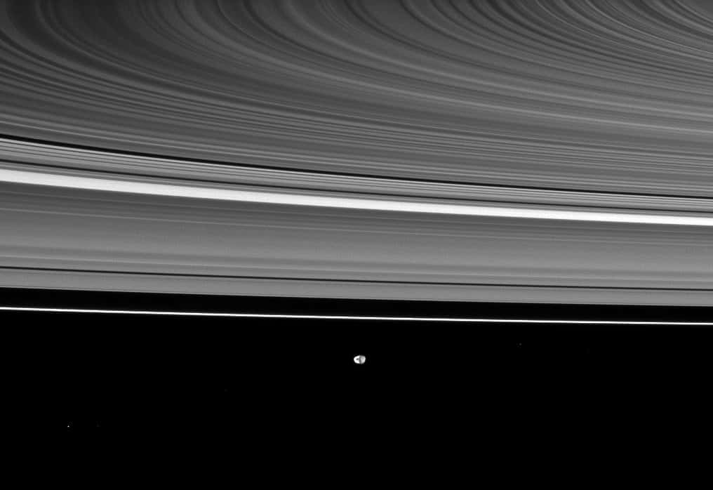 Les anneaux de saturne, vus par la <a href="//www.futura-sciences.com/fr/news/t/astronautique/d/cassini-sapprete-a-survoler-encelade-pour-la-24e-fois_26319/" title="Cassini s&#039;apprête à survoler Encelade pour la 24e fois" target="_blank">sonde Cassini</a>, avec, au loin, le petit Janus (179 kilomètres de diamètre, découvert en 1966 par <a href="//www.futura-sciences.com/fr/news/t/astronomie/d/le-dernier-vol-daudouin-dolfus_25426/" title="Le dernier vol d&#039;Audouin Dollfus" target="_blank">Audouin Dollfus</a>), à 2,1 millions de kilomètres de l'engin spatial. © Nasa/JPL/<em>Space Science Institute</em>