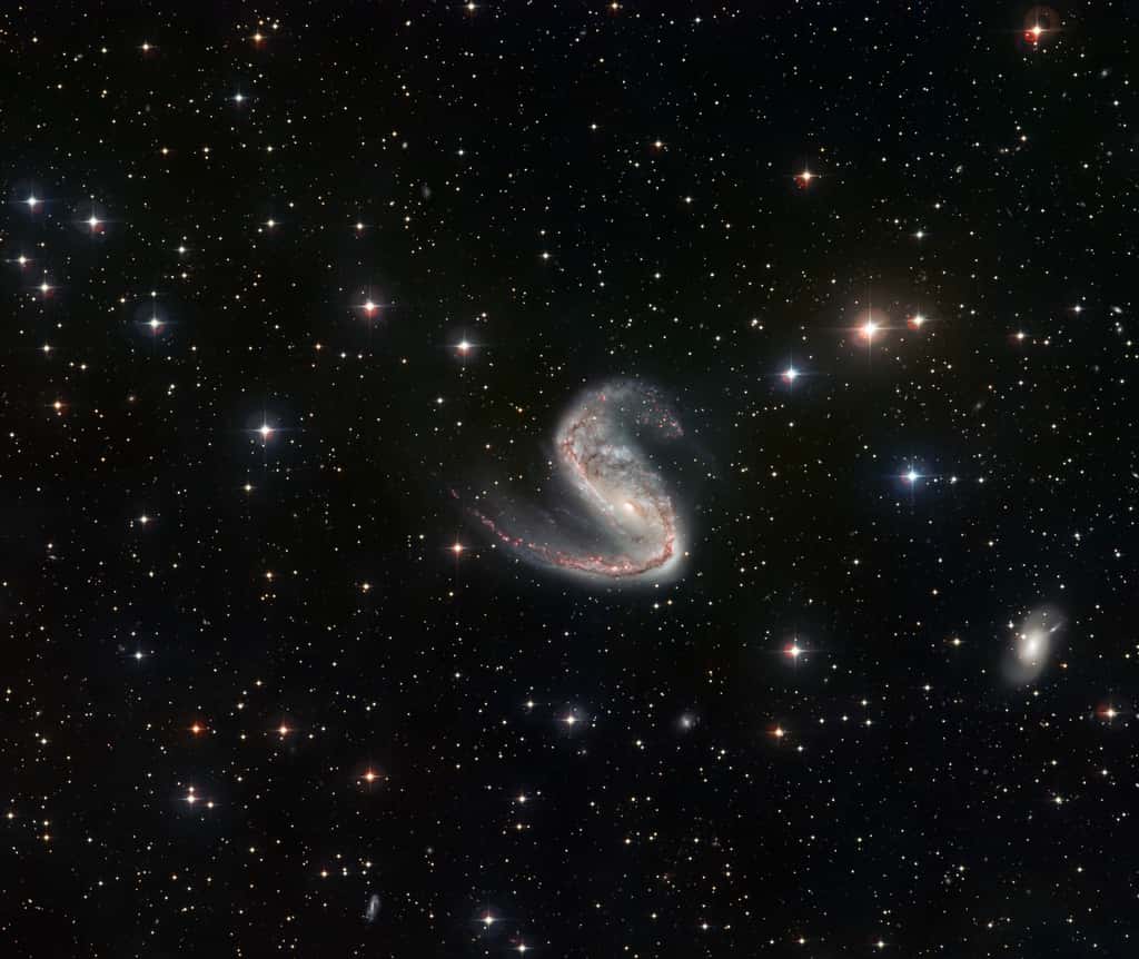 Ce plan large de la galaxie de l'Hameçon réalisé par le télescope de 2,2 mètres de diamètre de l'ESO permet de découvrir le champ environnant ainsi que la dissymétrie qui frappe les bras de NGC 2442. © ESO