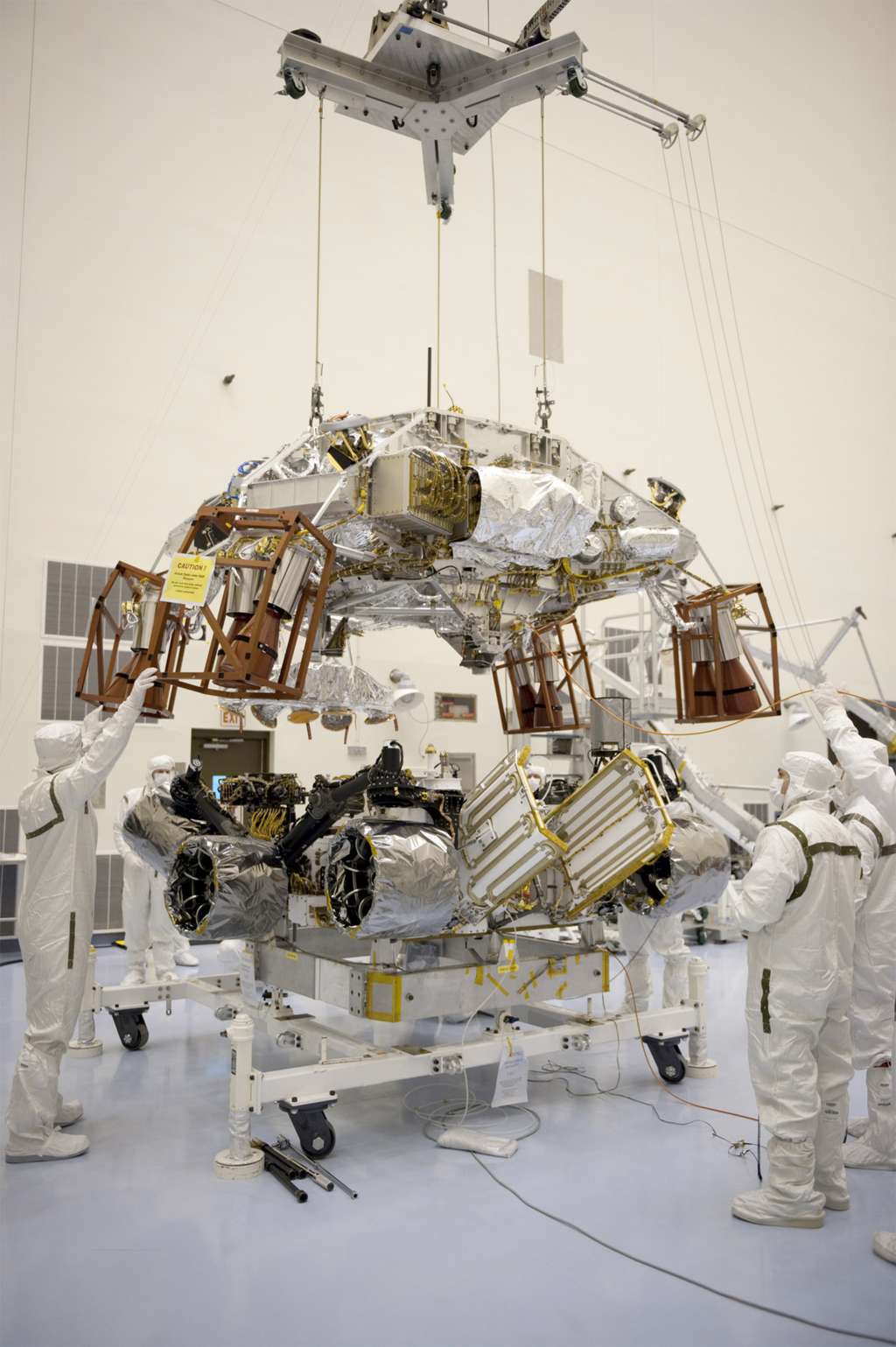  <br />À gauche, l'innovant système d'atterrissage Skycrane, qui doit devenir la norme pour se poser sur Mars, en cours d'installation sur le rover Curiosity. À droite, installation du cône arrière du bouclier (<em>backshell </em>en anglais), qui abrite également les parachutes. © Nasa/JPL-Caltech