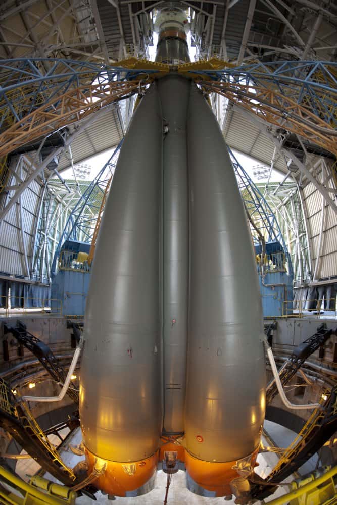 À l'abri dans le portique mobile, le lanceur Soyouz entièrement assemblé avec son étage supérieur Fregat, est préparé pour son lancement prévu le 20 octobre. Le lanceur ne repose pas sur sa table de lancement, comme Ariane 5. Il est maintenu par les quatre bras (bleus) au-dessus du carneau. Profond de 25 mètres, ce carneau a pour fonction d'évacuer les gaz de combustion. © Esa/S. Corvaja, 2011
