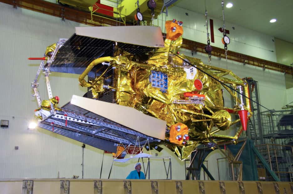 Phobos-Grunt en position horizontale. Le module de retour et la capsule de rentrée atmosphérique sont visibles à gauche, logés au sommet de la sonde, entre les deux panneaux solaires. Quant au module chinois, peu visible à l'image, il se situe sous la sonde, coincé entre les pieds. © Roscosmos