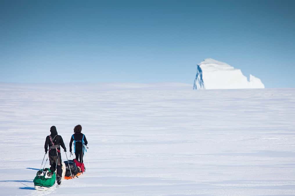 Julien Cabon et Alan Le Tressoler progressent sur la banquise, en 2011, le long de la côte est du Groenland. Devant eux, un iceberg de plus d'une trentaine de mètres de hauteur. © Raphaël Demaret
