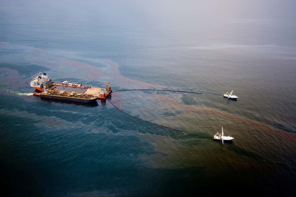 Le <em>Mighty Servant 3</em>, avec deux autres bateaux, en train de  récolter le pétrole d'une nappe, le 18 juin 2010. Au total, environ 120  millions de litres ont été récupérés. Ce type de pollution est clairement visible. L'entrée de molécule cancérigène dans les chaînes alimentaires l'est mois. © BP