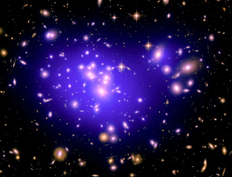 L'amas de galaxie Abell 1689 contient de la matière noire dont la distribution peut être déduite des effets de lentille gravitationnelle et être reconstituée à l'ordinateur. C'est ce qui a été fait sur cette image où l'on voit surimposée en fausse couleur violette la matière noire. © Nasa, Esa, E. Jullo (JPL/LAM), P. Natarajan (Yale) et J.-P. Kneib (LAM)