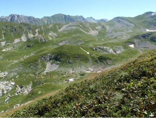 Le gouffre de Krubera-Voronya, dont l'entrée est indiquée par la flèche blanche, se situe dans le massif de l'Arabika au sein du Caucase occidental. Les points bas de la cavité sont également accessibles par deux autres entrées : le gouffre Kuybyshev et l'abîme Heinrich<em>. © </em>Sendra et Reboleira 2012, <em>International Journal of Speleology</em>
