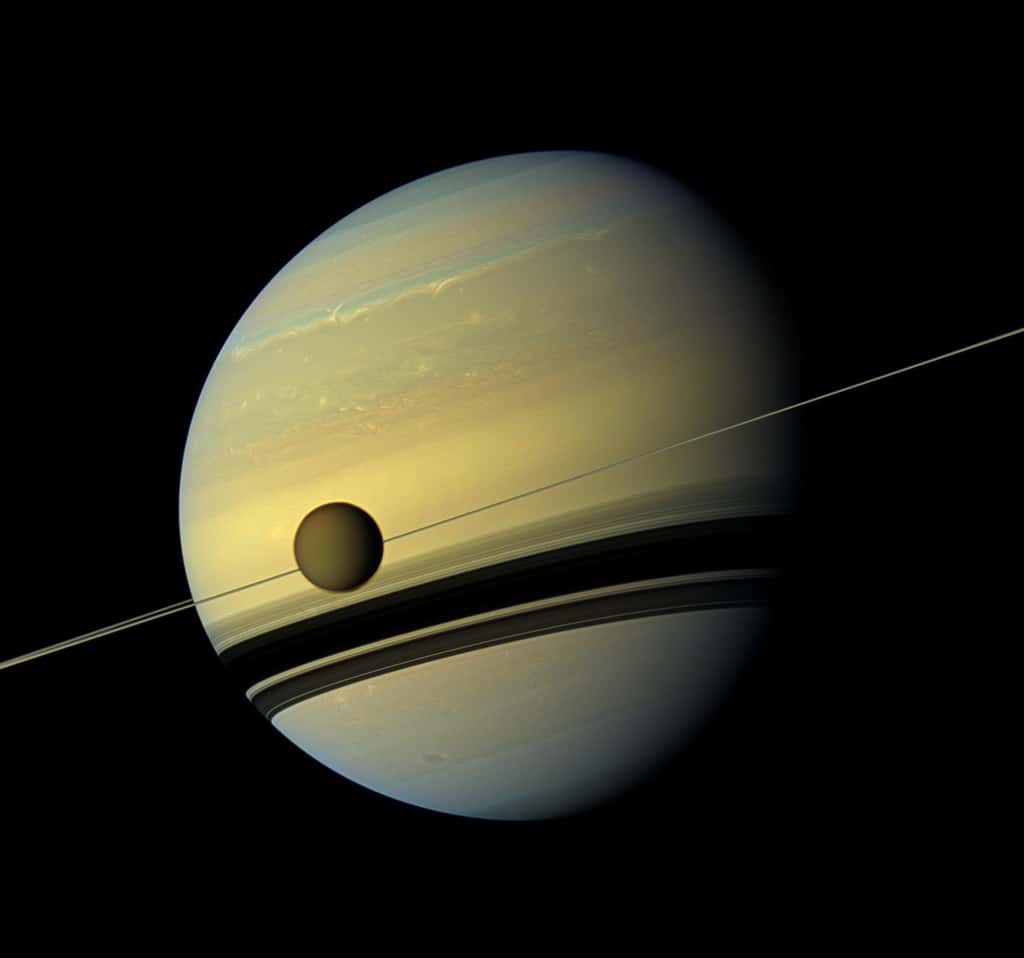 Sur cette image prise par Cassini, on voit Titan au premier plan. Les traces de terribles tempêtes en 2011 sont à peine visibles au second plan dans l'hémisphère nord de Saturne. © Nasa
