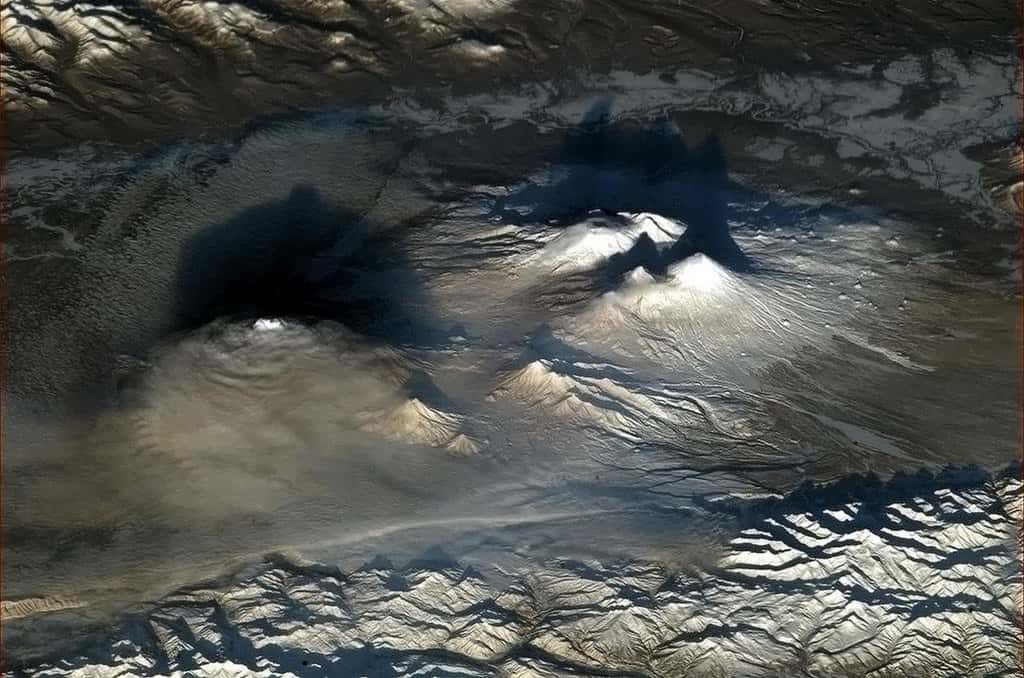 À gauche dans les nuages, le volcan Tolbatchik. Au fond de l'image à droite, le volcan bouclier Ushkovsky. Devant lui, le Kliouchevskoï. En avant-plan, deux volcans de taille plus modeste. © Nasa, CSA, Chris Hadfield