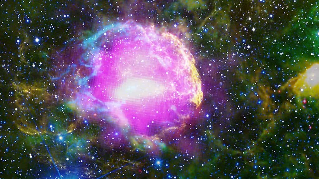 Cette image composite, réalisée avec des photographies prises par plusieurs télescopes, montre le reste de supernova IC 443, situé à 5.000 années-lumière du Soleil dans la constellation des Gémeaux. On l'appelle parfois la nébuleuse de la Méduse. Les émissions de rayons gamma observées par Fermi sont ici montrées en magenta et celles dans le visible en jaune. Les autres couleurs correspondent à des émissions dans l’infrarouge. © NASA/DOE/Fermi LAT Collaboration, NOAO/AURA/NSF, JPL-Caltech/UC