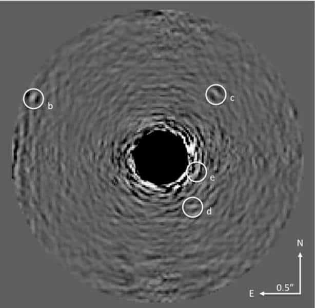 La technique de coronographie initiée par Bernard Lyot au milieu du XX<sup>e</sup> siècle pour observer la couronne solaire permet aujourd'hui d'imager directement des exoplanètes. On distingue quatre planètes autour de HR 8799, numérotées b à e, a étant l'étoile. La lumière de celle-ci a été soustraite de l'image, comme le montre la zone sombre au centre, révélant les planètes bien moins lumineuses. © <em>American Museum of Natural History</em>