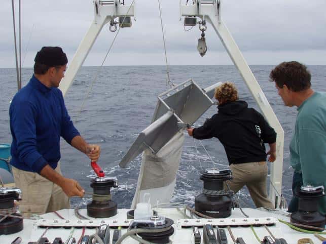 Le <em>Manta trawl</em> est mis à l'eau depuis l'arrière du bateau. Il est équipé d'ailes porteuses sur les côtés, qui permettent de garder l'ouverture du filet à l'interface air-mer. Les filets récupèrent donc un certain volume de débris qui stagnent en surface de l'eau. De gauche à droite, les chercheurs Marcus Eriksen, Jody Lemmon et Charles Moore. © <em>Algalita Marine Research Institute</em>