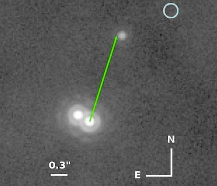 Sur cette image, on voit l'étoile double 2MASS0103(AB) en bas à gauche. Une première détection de 2MASS0103(AB)b avait été faite en 2002, et elle se trouvait alors exactement au bout de la flèche verte par rapport à la binaire. En 2012, elle s’est très légèrement décalée. Le cercle bleu en haut à droite montre la place qu'aurait dû occuper 2MASS0103(AB)b en 2012 du fait du mouvement de l'étoile double si l'astre n'était associé en 2002 que par l'effet du hasard à la binaire. © ESO