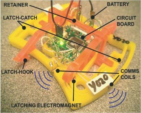 Ceci est un robot ! La puce électronique, au centre, perçoit la proximité de voisins éventuels par un contact radio et peut lever ou baisser un grappin, de couleur orange.