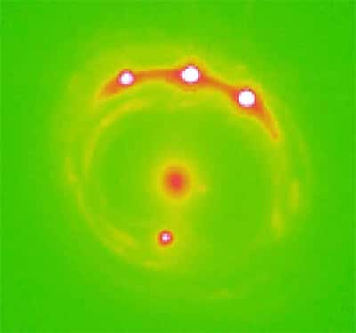 Sur cette image en fausses couleurs, obtenue en lumière visible mais amplifiée par une lentille gravitationnelle, on voit quatre points rouges correspondant au Quasar RXJ1131-1231. Au centre, il s'agit de la galaxie responsable de l'effet de lentille gravitationnelle.<br />Crédits : Ohio State University