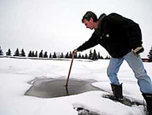Le trou (déjà partiellement gelé) creusé par la météorite dans la glace recouvrant l’étang du terrain de golf de <em>Spruce Grove</em>. Crédit : <em>The Sun</em>