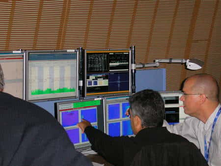 Cliquez pour agrandir. Des physiciens du Cern devant les copies des écrans de contrôle dans la salle de conférence du Globe. Crédit : Laurent Sacco/Futura-Sciences