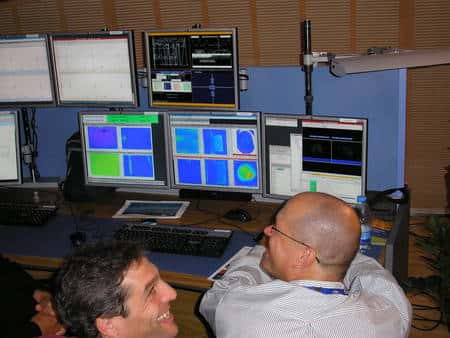 Cliquez pour agrandir. Des physiciens du Cern devant les copies des écrans de contrôle dans la salle de conférence du Globe. Crédit : Laurent Sacco/Futura-Sciences