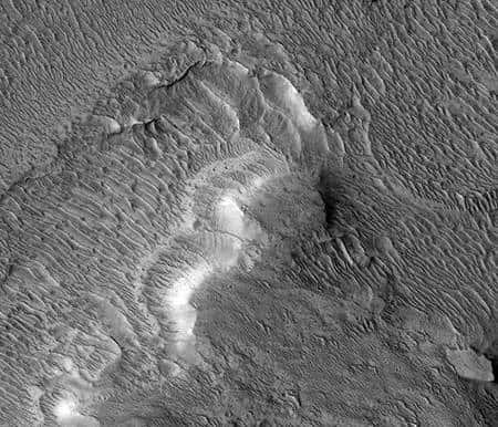Cette image d’environ un kilomètre de base prise par l’instrument HiRise à bord de <em>Mars Reconnaissance Orbiter</em> de la Nasa montre un écoulement en delta formé par la rivière Nanedi dans le fond d’un cratère anonyme des Hautes terres de Xanthe. Les couches d’alluvions horizontales empilées sont épaisses de seulement quelques mètres chacune. Le reste de la surface est maintenant caractérisé par des dunes sculptées par le vent martien. Crédit Nasa