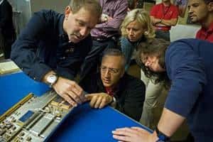 Mike Massimino (accroupi) à côté de l'astronaute John Grunsfeld (à gauche de l'image), avec l'équipe d'ingénieurs, en train d'étudier un modèle de test du spectromètre STIS, qui doit être réparé lors de la prochaine mission de maintenance, initialement prévue en octobre 2008. © Nasa