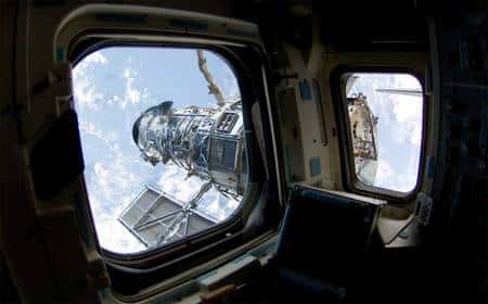 Le télescope spatial Hubble, vu par les hublots d'<em>Atlantis</em>. Crédit Nasa