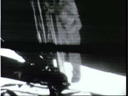 Neil Armstrong, filmé par la caméra fixée sur le LM, descend l'échelle. © Nasa