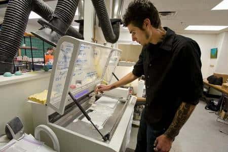 Grant Marchelli prépare son imprimante 3D en étalant une fine poudre de verre. © <em>University of Washington</em>