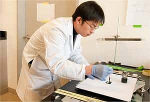 Bing Hu prépare une batterie en déposant une encre sur du papier ordinaire, laquelle fixera les nanotubes de carbone sur les fibres de cellulose. La surface pourra ainsi être chargée en électricité. © L.A. Cicero/<em>Stanford University</em>