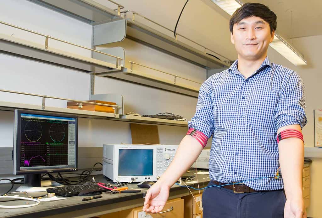 Cet ingénieur de l’université de Californie à San Diego porte deux prototypes de bracelets conçus à partir d’un fil de cuivre enrobé de PVC. Pour fonctionner, il faut que la bobine soit enroulée autour d’un membre afin que les champs magnétiques puissent se propager. © UC San Diego