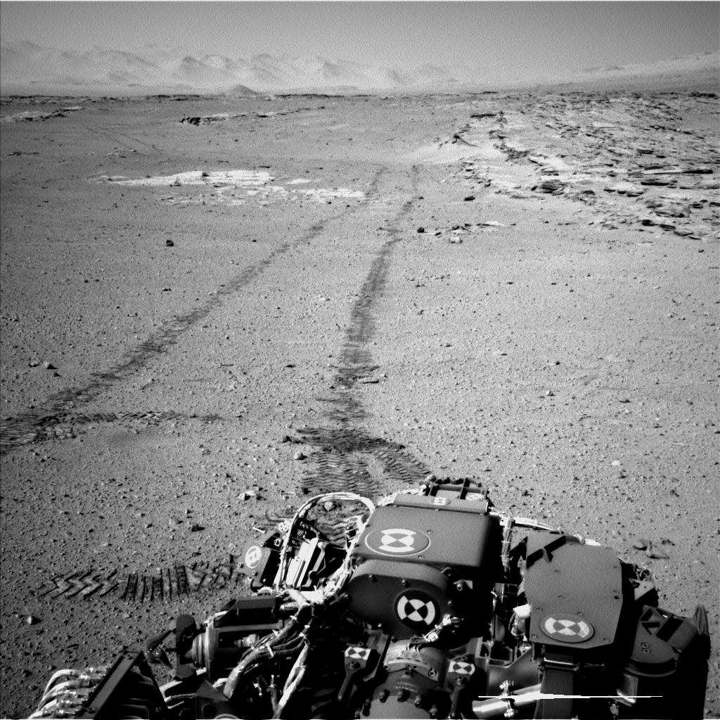 Image prise le 19 février, lors du 548<sup>e</sup> jour de Curiosity sur Mars. Après avoir profité du panorama où le mont Sharp écrase l'horizon, le rover a repris la route, toujours en marche arrière. À droite, on reconnaît les alignements de roches du site nommé Junda, où il a fait une pause quelques instants plus tôt. À l'arrière-plan, on distingue les remparts qui bordent le vaste cratère Gale. © Nasa, JPL-Caltech