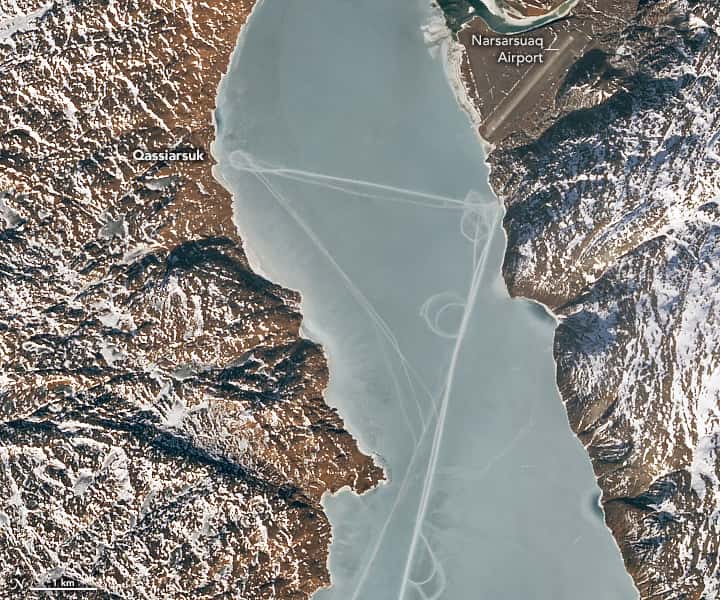 De part et d’autre du fjord glacé de Tunulliarfik (Groenland), deux villes semblent reliées par des traces en ligne droite. © Lauren Dauphin, Nasa Earth Observatory, Landsat, US Geological Survey