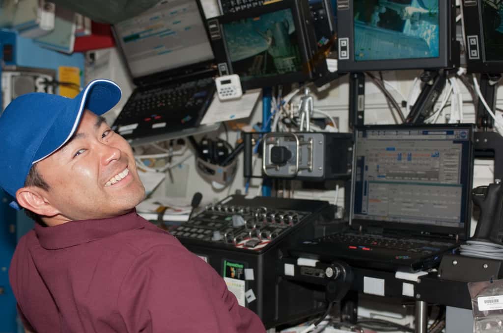 Aki Hoshide au contrôle du CanadArm2 depuis le module Destiny lors de l'installation du module Kibo (on voit le module tenu à bout de bras dans l'écran en haut à droite de l'image). © Nasa
