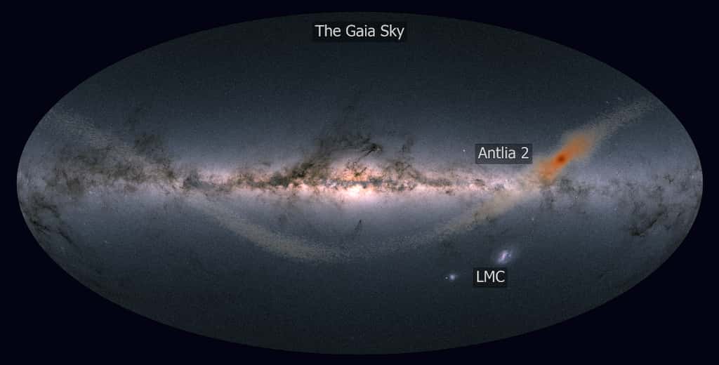 Antlia 2 est une géante parmi les galaxies naines car diffuse mais de faible masse. Alors qu'Antlia 2 est en orbite autour de la Voie lactée, ses étoiles sont arrachées par les forces de marée de la Voie lactée. Les étoiles orange montrent les résultats d’un modèle informatique d’Antlia 2 soumis à ces forces qui produisent donc une sorte de courant d'étoiles, dit courant de marée. L’arrière-plan montre la vue du satellite Gaia sur l’ensemble du ciel nocturne. Le Grand Nuage Magellan (LMC) est visible sous le disque de la Voie Lactée – bien que de taille similaire à Antlia 2, le LMC est 10.000 fois plus lumineux ! © J. Sanders (Cambridge, UK) <em>based on the image by Gaia Data Processing and Analysis Consortium</em> (DPAC)/A. Moitinho/A. F. Silva/M. Barros/C. Barata, Université de Lisbonne, Portugal /H. Savietto, Fork Research, Portugal