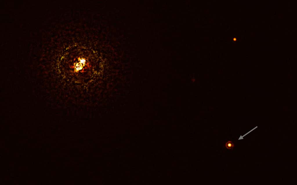 Cette image montre <em>b Centauri</em>, la paire d'étoiles la plus massive observée à ce jour abritant une planète, et sa planète géante <em>b Centauri b</em>. La paire d'étoiles est l'objet brillant dans le coin supérieur gauche de l'image, les anneaux lumineux et sombres qui l'entourent étant des artefacts optiques. La planète, visible comme un point brillant dans le coin inférieur droit de l'image (indiquée par une flèche), est dix fois plus massive que Jupiter. L'autre point brillant de l'image (en haut à droite) est une étoile de fond. En prenant différentes images à différents moments, les astronomes ont pu distinguer la planète des étoiles de fond. L'image a été prise à l'aide d'un coronographe qui a bloqué la lumière du système d'étoiles massives et a permis aux astronomes de détecter la faible planète. © ESO/Janson et <em>al.</em>