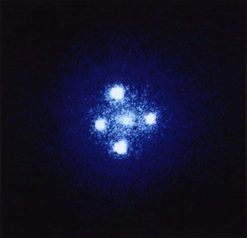 La croix d'Einstein (Q2237+030 ou QSO 2237+0305) est un quasar à lentille gravitationnelle qui se trouve directement derrière le centre de la galaxie ZW 2237+030, appelée lentille de Huchra du nom de son découvreur, l'astronome John Huchra décédé depuis. Quatre images du même quasar distant (plus une au centre, trop sombre pour être vue) apparaissent au milieu de la galaxie de premier plan en raison d'une forte lentille gravitationnelle. Clairement, ce ne peut être un des trous de ver chargés découverts par les chercheurs chinois car on observe quatre images. © Nasa, Esa  
