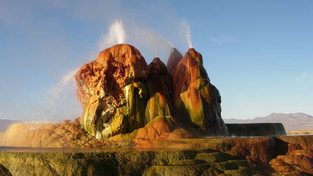 Le Fly Geyser dans le Nevada, aux États-Unis. Le Fly Geyser, aussi connu comme le Fly Ranch Geyser, se trouve dans le désert de Black Rock, au Nevada (États-Unis). Ce geyser n’est pas vraiment naturel. Il est apparu vers 1964 suite au forage d’un puits cinquante ans auparavant. Le puits n’ayant pas été correctement façonné, une source géothermique s’est infiltrée et les minéraux dissous se sont peu à peu empilés pour former ce monticule composé de trois cônes de couleur rouge orange qui crachent de l’eau en permanence. © Ken Lund, CC by-sa 2.0