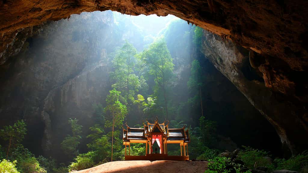 La grotte de Phraya Nakhon, en Thaïlande. Cette vue de la grotte de Phraya Nakhon située dans le parc national marin de Khao Sam Roi Yot, en Thaïlande, permet de découvrir un élégant pavillon dédié au roi Rama V, qui a été édifié sur un petit tertre d’argile rougeâtre. La vaste caverne de roche calcaire a été creusée par le ruissellement des eaux pluviales et sa partie supérieure est percée de plusieurs ouvertures au travers desquelles s’infiltre la lumière du jour. Une arche, sorte de pont fantasmagorique, surplombe la grotte dans laquelle croît une végétation luxuriante. © Niels Mickers, CC by 3.0 NL