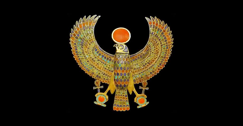 Le pectoral du pharaon, l'un des joyaux retrouvés au plus près de la momie. Ce bijou est un ornement vestimentaire ou corporel, orné de pierres semi-précieuses, turquoise, cornaline, lapis-lazuli, et de pâte de verre multicolore. Comme son nom l’indique, ce bijou pectoral se place sur le thorax, considéré chez les civilisations anciennes comme le siège de l’âme. Porté à cet endroit, il est supposé assurer la protection magique ou divine, en l’occurrence, ici, celle du dieu Horus. Le faucon représente le dieu Horus, portant le disque solaire et déployant ses ailes en signe de souveraineté. Dans ses griffes, des attributs des dieux égyptiens, la croix Ânkh, signe de vie, et l’anneau Shen, signe d’éternité. Ce pectoral fait partie de 143 bijoux retrouvés, enfouis dans les bandelettes entourant la momie. © Jean-Pierre Dalbéra, Flickr, CC by 2.0