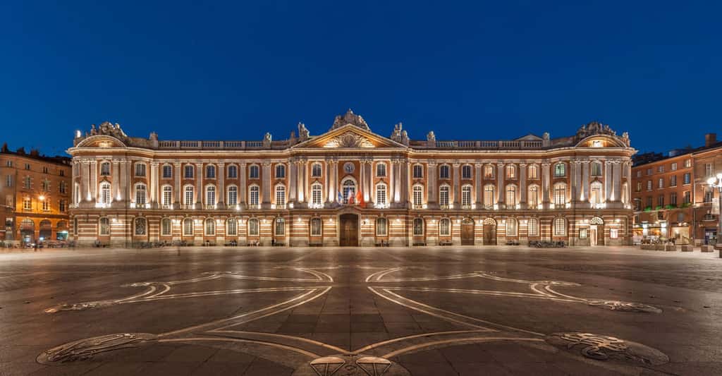 Le Capitole à Toulouse et la place du même nom. Il s’agit d’un lieu incontournable du tourisme en Haute-Garonne. On distingue au sol la croix conçue par Raymond Moretti. © Blieusong, Flickr, CC by-sa 2.0 
