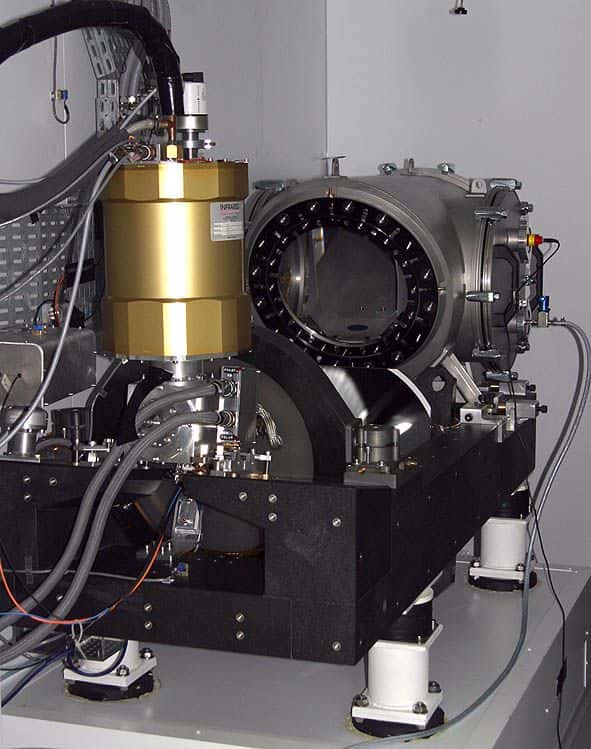 Le spectrographe Sophie, sur ses quatre pieds antivibrations. Il reçoit la lumière du télescope par quatre fibres optiques (grises, en haut à gauche). La lumière est envoyée à travers le hublot (une lame de Schmidt, au centre). © OAMP