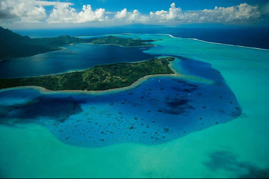 Bora Bora, Polynésie française, France (16°31’ S - 151°46’ O). L’archipel des Iles Sous-le-Vent, en Polynésie française, territoire d’outre-mer depuis 1946, abrite cette île de 38 km<sup>2</sup> dont le nom signifie « la première-née ». Elle est constituée de la partie émergée du cratère d’un ancien volcan, vieux de 7 millions d’années, entourée d’un récif barrière de corail sur lequel se sont développés des îlots coralliens couverts d’une végétation comprenant principalement des cocotiers. © Yann Arthus-Bertrand - Tous droits réservés
