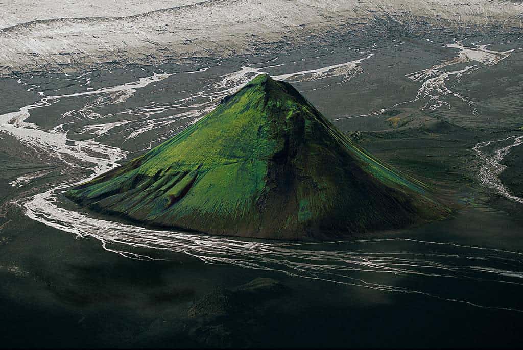 Le Maelifell en bordure du glacier Myrdalsjökull, Islande (63°51’ N - 18°13’ O). Au sud de l’Islande, ce cône volcanique, constitué de cendres et de projections de lave solidifiées, est né de l’une des nombreuses éruptions survenues sous la calotte du glacier Myrdalsjökull avant que celui-ci ne se retire. Délivré du glacier il y a environ 10.000 ans, le Maelifell est maintenant baigné par les rivières qui s’en écoulent. Son cône parfait, qui s’élève à 200 m au-dessus de la plaine, est recouvert de mousses du genre grimmia qui prolifèrent sur les laves refroidies et dont la couleur varie du gris argent au vert lumineux selon le taux d’humidité du sol. © Yann Arthus-Bertrand - Tous droits réservés