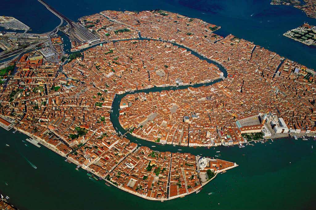 Vue générale de la ville de Venise, Vénétie, Italie (45°25’ N - 12°45’ E). Venise est un archipel de 118 îles, séparées par 160 canaux qu’enjambent plus de 400 ponts, située au centre d’une lagune séparée de la mer par un cordon littoral entrecoupé par trois passes. Sa principale artère, le Grand Canal, est bordée par une centaine de palais de la Renaissance et de l’époque baroque érigés par les riches marchands vénitiens. Ils témoignent de l’importance prise par ces commerçants quand Venise s’est ouverte sur le monde extérieur. © Yann Arthus-Bertrand - Tous droits réservés