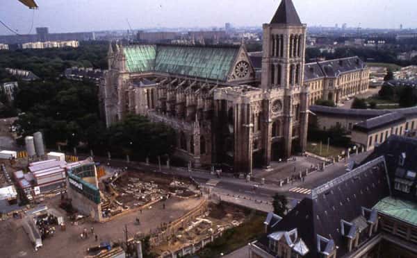 Fig. 3 - Vue de la basilique Saint-Denis avec un chantier de fouille ouvert sur le cimetière extérieur au nord de l'édifice (1990). © UASD Olivier Meyer